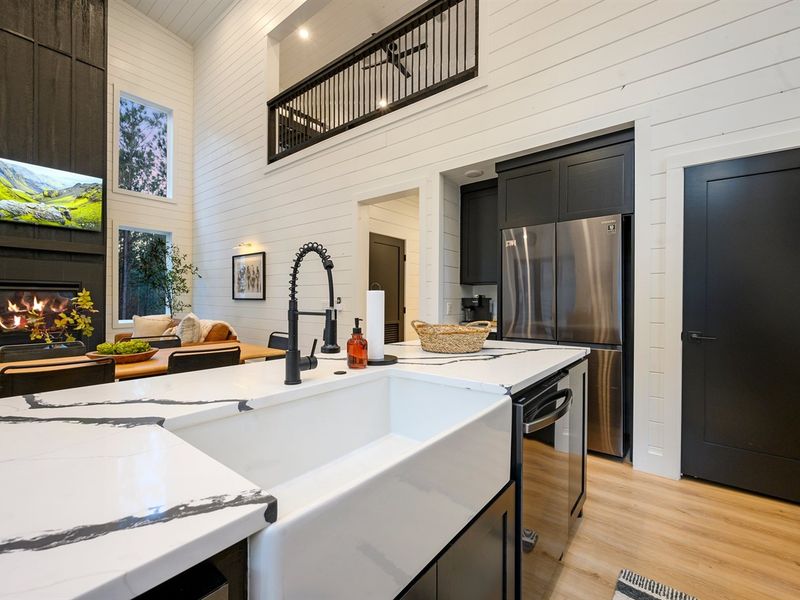 The modern farmhouse kitchen features sleek black cabinetry, warm wood accents, and stunning quartz countertops.