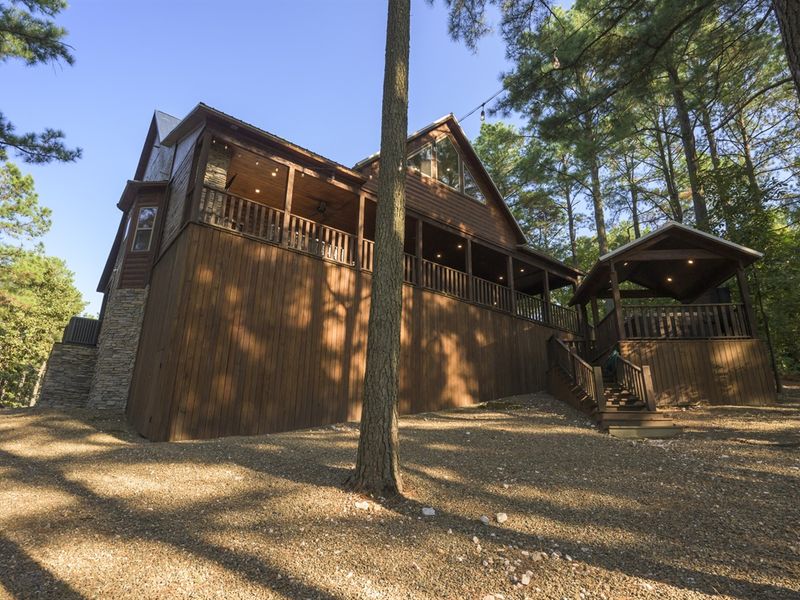 Cozy wooden cabin surrounded by trees, featuring a spacious deck and outdoor seating, ideal