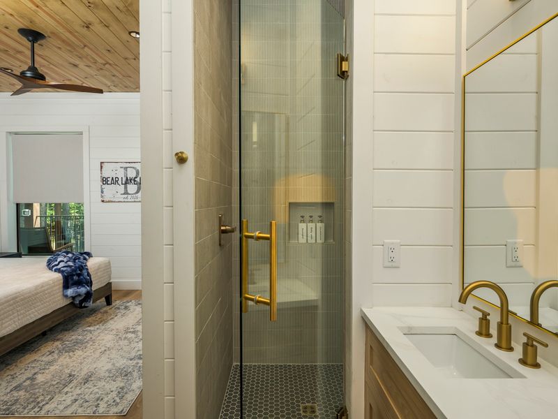 Step into the spacious walk-in shower, featuring sleek tilework, a rainfall shower head, and convenient built-in amenities.