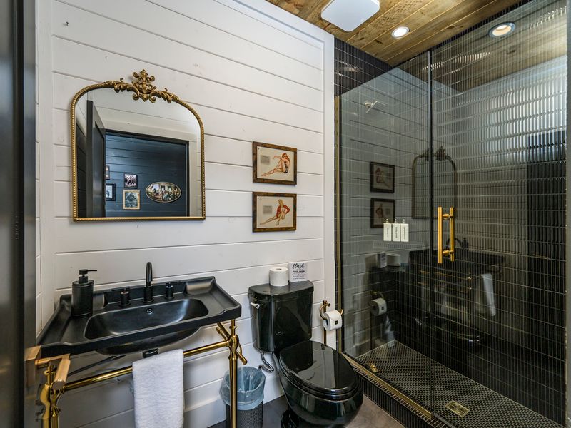 Black fixtures, gold accessories, large walk-in shower continue the nostalgic feel of the speakeasy.