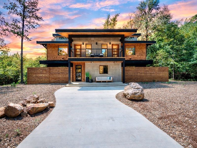 Your Hochatown getaway starts here—sleek design, peaceful woods, and a picture-perfect entrance at golden hour.