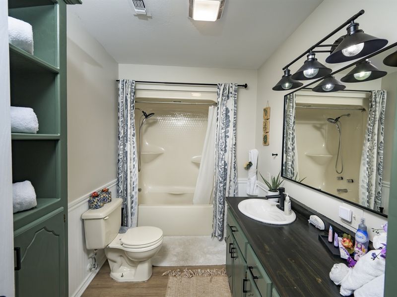 Cozy and modern bathroom interior showcasing a shower, vanity, and shelving, highlighting comfort and convenience
