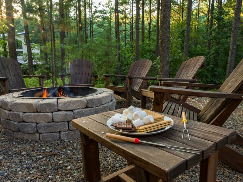 Cozy outdoor fire pit surrounded by wooden chairs, with a plate of s'mores ingredients including