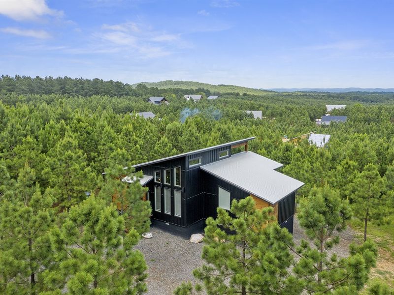 The cabin sits atop a ridge, showcasing breathtaking views of the Kiamichi Mountains.