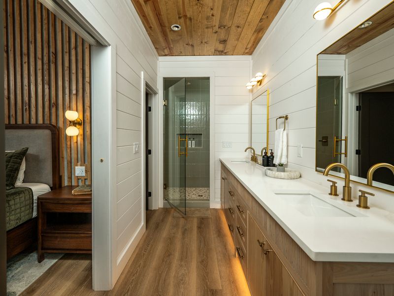 Beautiful double vanity with quartz countertops, gold fixtures, and custom wood cabinetry.