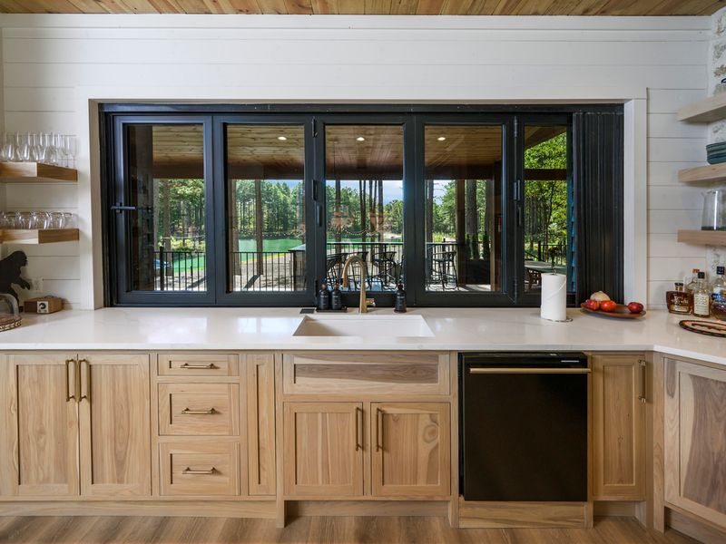 Large kitchen window showcasing a wooded lakeside view, complementing the beautiful chef’s kitchen
