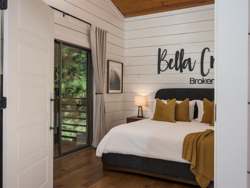 A peaceful bedroom retreat with forest views, warm wood tones, and direct deck access—designed for rest and relaxation in Broken Bow