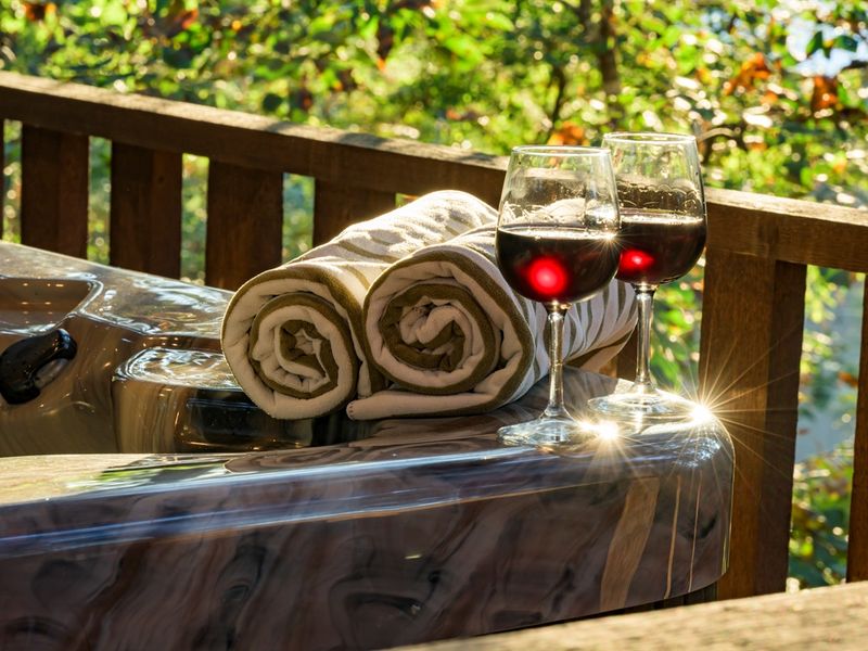 Cozy scene featuring two glasses of red wine beside rolled towels on the edge