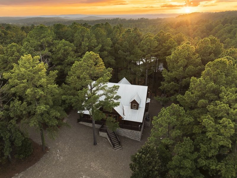 Aerial view of a cozy cabin nestled among lush green trees, evoking comfort and convenience