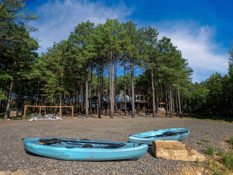 A private waterfront escape featuring kayaks and a dock, nestled among towering pines, showcasing