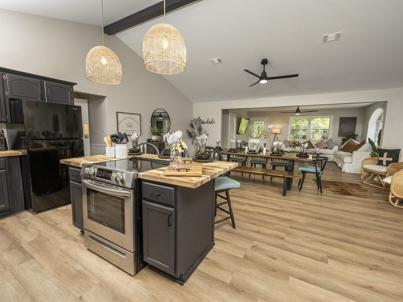 Spacious modern kitchen with an island, stainless steel appliances, and wooden floors, leading