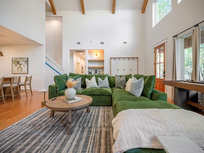 Bright windows, warm wood tones, and a cozy green sectional create the perfect retreat for connection. ✨🌲