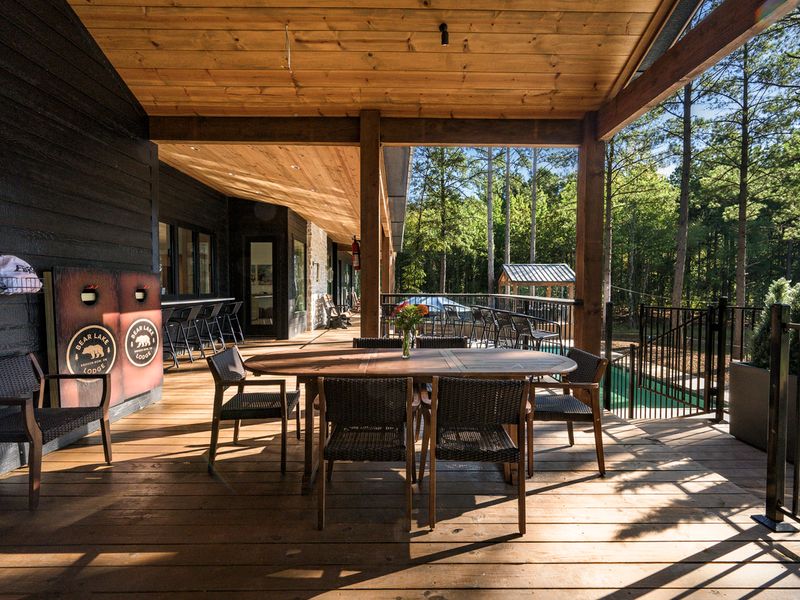 Spacious covered deck at Bear Lake Lodge features outdoor dining table, seating, and bar area