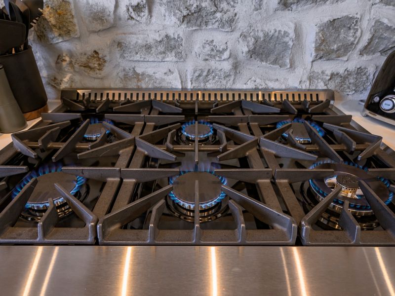 Close-up of a deluxe range with lit burners, highlighting the well-appointed chef’s kitchen at Bear