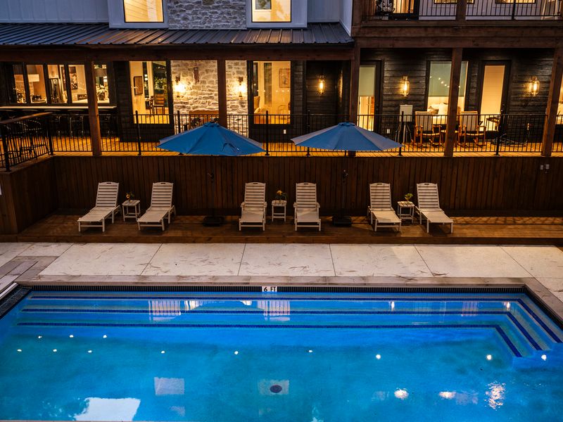 After sunset, the illuminated pool becomes a spectacular centerpiece for evening swims and relaxing nights beneath the trees.