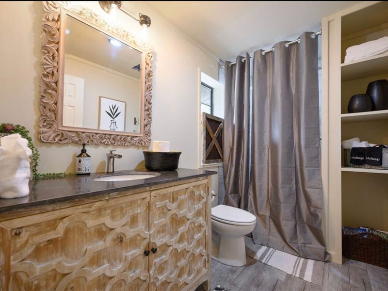 A tranquil private bathroom ensuite the bunk room featuring a toilet, shower, sink, and mirror.