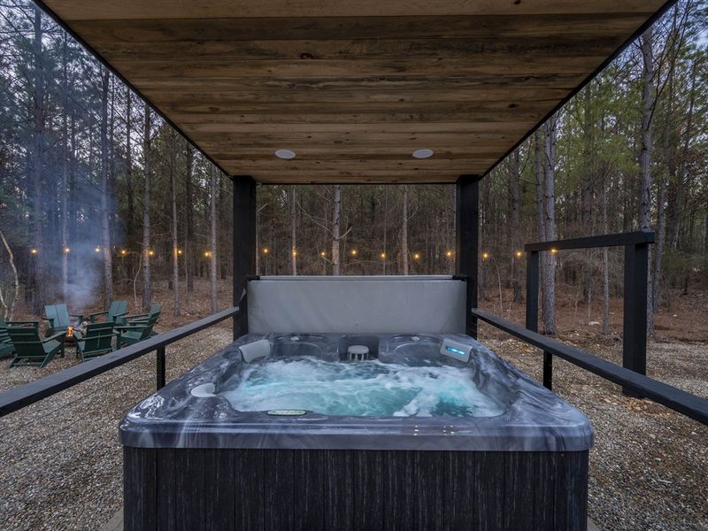 "Unwind in the covered hot tub, surrounded by high-end outdoor furniture, blending comfort with the beauty of nature."