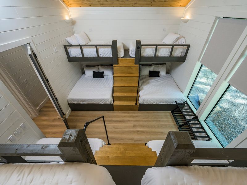 A unique overhead view highlights the open loft design, multiple sleeping spaces, and large windows overlooking the outdoors.