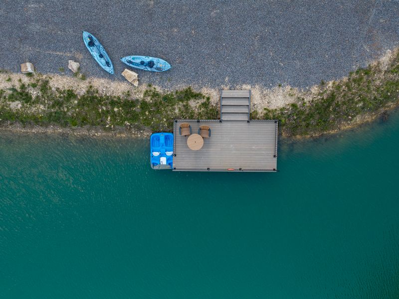 Aerial view of a private dock with a blue paddle boat and kayaks, surrounded