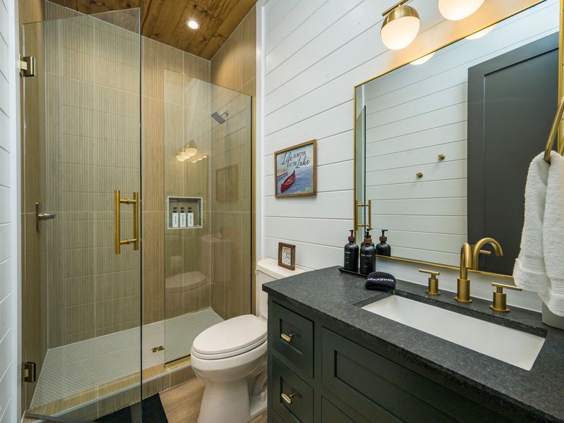 A bright, stylish bathroom featuring a spacious walk-in shower, modern finishes, and warm wood accents.