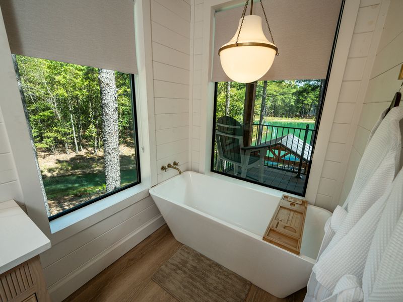 The luxurious soaking tub offers a tranquil retreat with picturesque views of the lake and private outdoor deck.