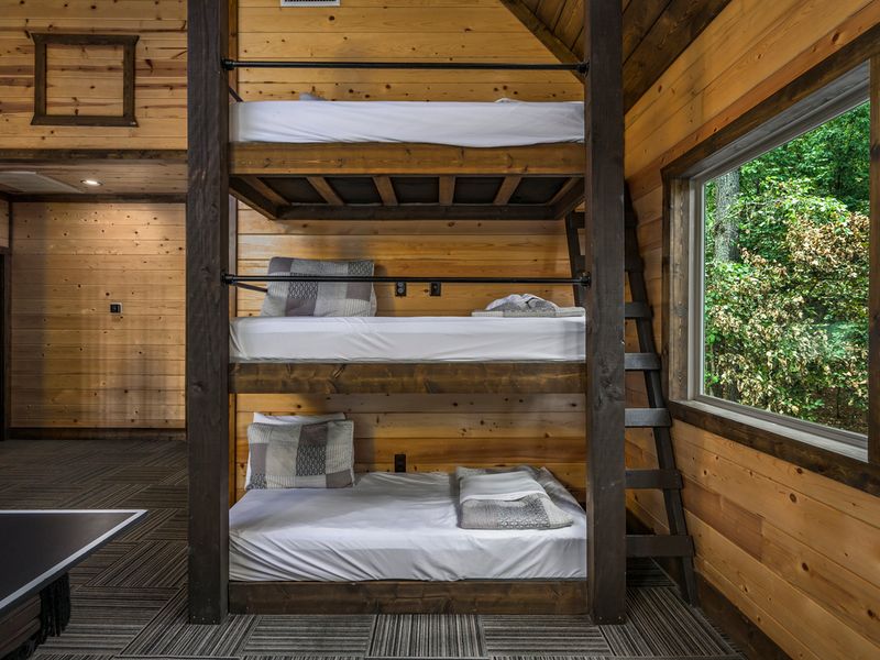Cozy triple bunk beds with rustic wood finishes and beautiful forest views—perfect for kids and teens.