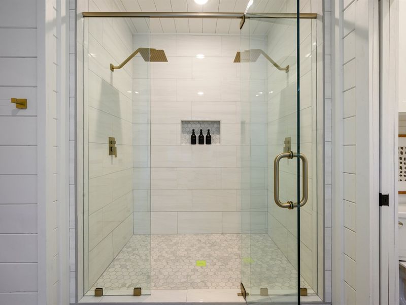 A spacious glass walk-in shower with dual rainfall showerheads offers a luxurious experience.