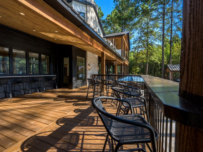 Spacious covered deck featuring stylish bar seating and a scenic view of the wooded surroundings
