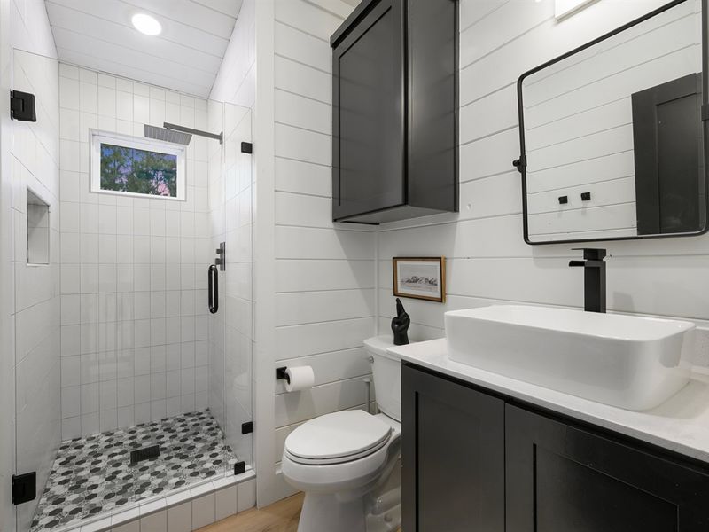 A glass walk-in shower with a rainfall showerhead adds a spa-like touch to the loft bathroom