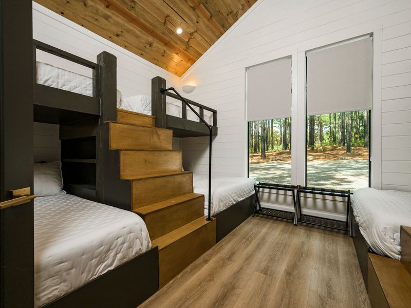 A cozy lower-level bedroom tucked beneath the loft, featuring crisp white bedding and rustic wood accents.