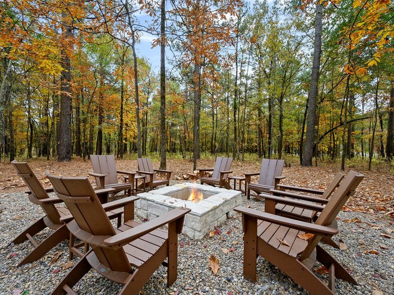 Spacious outdoor fire pit with Adirondack seating and peaceful forest views—perfect for s’mores, conversations, and relaxing evenings during your Broken Bow stay. 🌲🔥