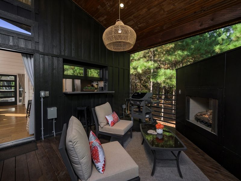 Unwind fireside in the treetops — this covered patio blends forest views, cozy seating, and open-air serenity.