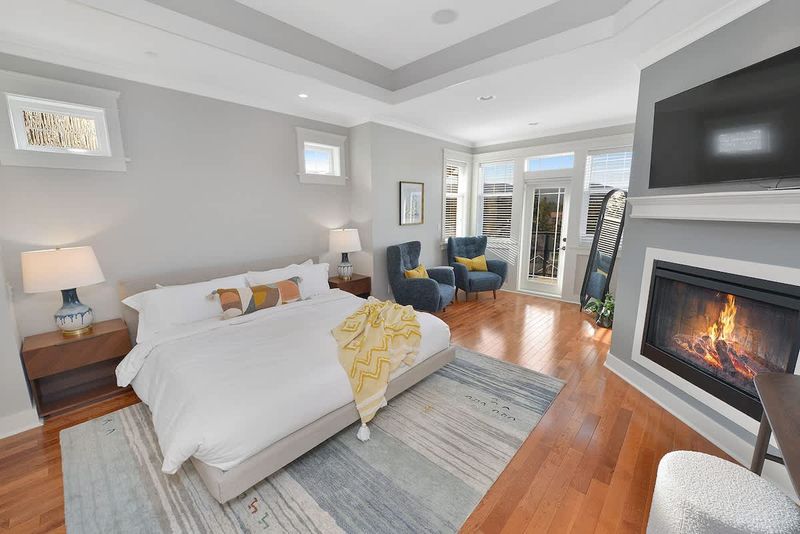 Primary bedroom king bed with private deck access and electric fireplace.