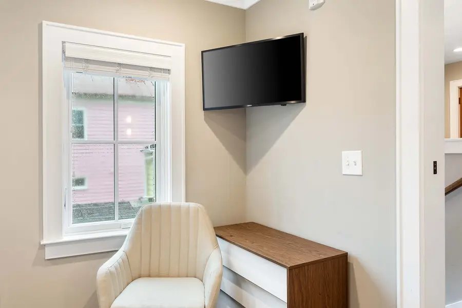 Bedroom 2: Bright and inviting with a queen bed, TV, reading chair, and en-suite bath.