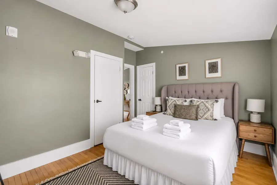 Bedroom 2: Bright queen bedroom with a TV and oversized windows.
