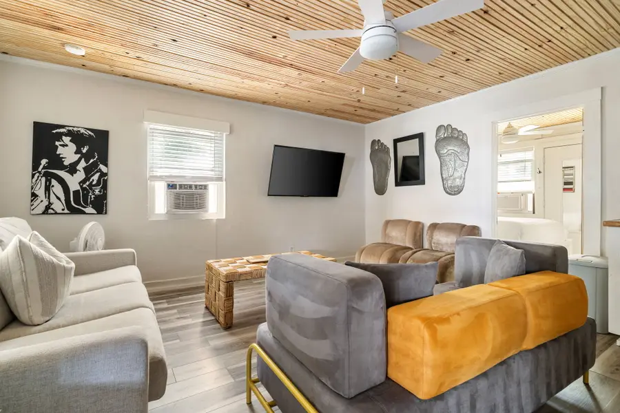 Gather in the bright and spacious living room, featuring cozy seating, a large TV, and walls of windows that fill the space with natural light.