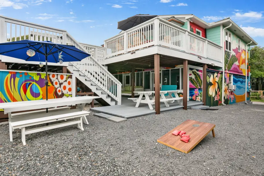 Enjoy endless outdoor living with spacious dining and lounge areas, cornhole, a hanging sofa, egg chair, lounge chairs, and a grill, all just steps from the beach.