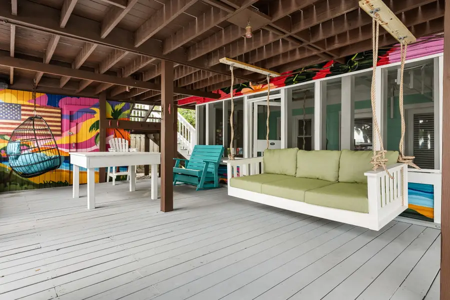 Enjoy endless outdoor living with spacious dining and lounge areas, cornhole, a hanging sofa, egg chair, lounge chairs, and a grill, all just steps from the beach.