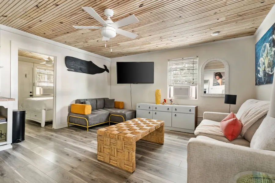 Gather in the bright and spacious living room, featuring cozy seating, a large TV, and walls of windows that fill the space with natural light.