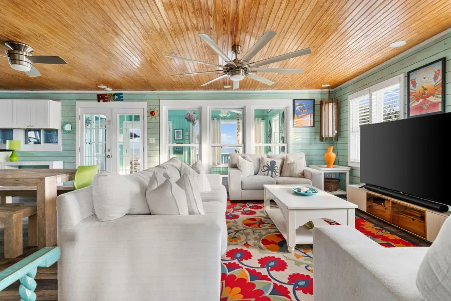 Gather in the bright and spacious living room, featuring cozy seating, a large TV, and walls of windows that fill the space with natural light.