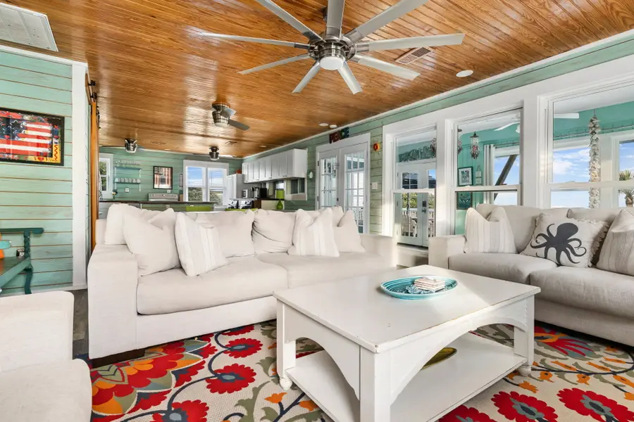 Gather in the bright and spacious living room, featuring cozy seating, a large TV, and walls of windows that fill the space with natural light.